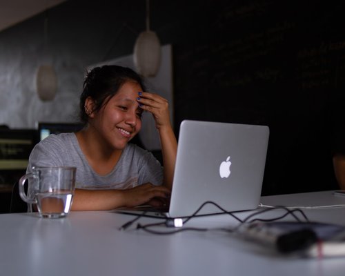 A person working comfortably on a laptop near a large window with natural light in Lima