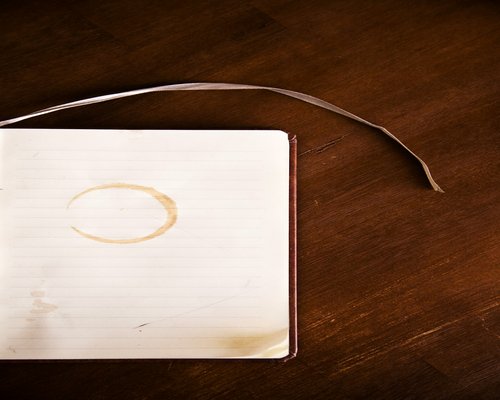 Close up of a coffee cup and notebook on a wooden desk with soft lighting